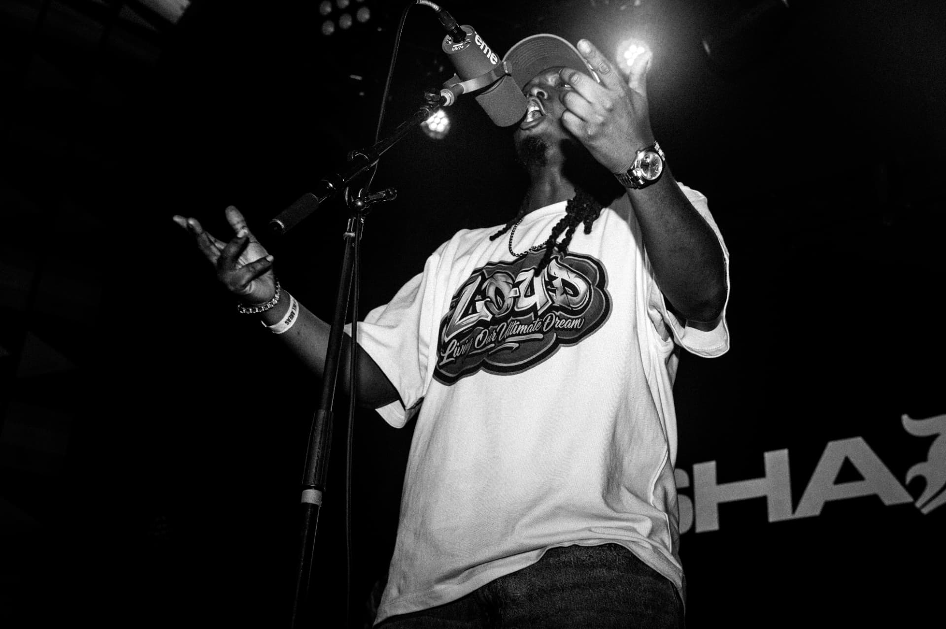 Rah Tha Ruler performing on stage in a LOUD tee